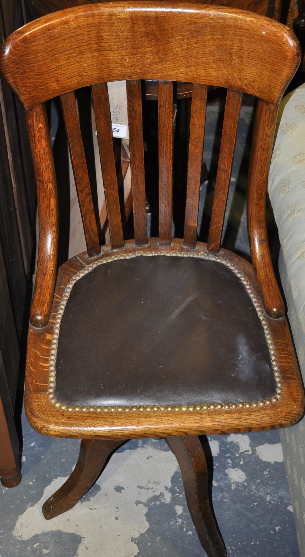 An early 20th century oak office swivel chair, the pad seat upholstered in leather.