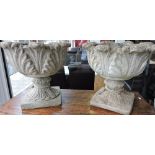 A pair of reconstituted stone garden urns with acanthus cast circular bodies on square plinths,