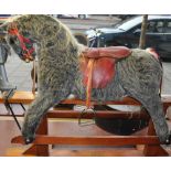 A Pegasus Toys, rocking horse, with a grey plush body and red leather saddle and tack,