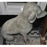 A pair of reconstituted garden ornaments models as seated hounds,