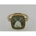 A 9ct gold dress ring with central peridot and diamond shoulders.