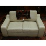 A Contemporary cream leather two-seater sofa.