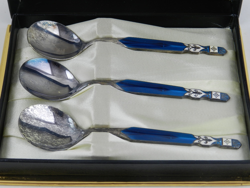 A cased set of three Mitsui stainless steel and enamelled teaspoons.