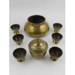 A Middle Eastern brass and white metal inlaid sugar pot, and six cups, together with one Middle