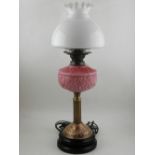 A VIctorian oil lamp, having opaque white shade and pink glass reservoir above reeded brass