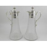 A pair of cut glass claret jugs, having silver plate handles and lids. H.30cm