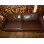 A Contemporary brown leather three seater sofa, raised on cast metal supports.