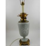 A 20th century porcelain and brass mounted oil lamp, later converted to electricity.