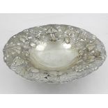 A Continental white metal dish, the pierced edge repousse decorated with fruit, raised on