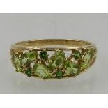 A 9 carat yellow gold, green citrine, and emerald cluster band ring.