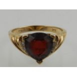 A yellow metal garnet and diamond dress ring, the shank stamped 14K.