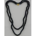 An opera length strand of black AAA pearls, with a 14 carat yellow gold clasp.