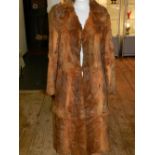 A full length rabbit fur coat, coloured with orange tones.