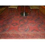 A red ground Afghan carpet, having three rows of elephant pad medallions to centre,