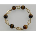 A yellow metal and tigers eye beaded bracelet.