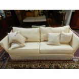 A Contemporary drop end two-seater sofa, upholstered in a cream fabric.