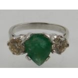 A white metal emerald and diamond dress ring, the shank stamped 18ct.