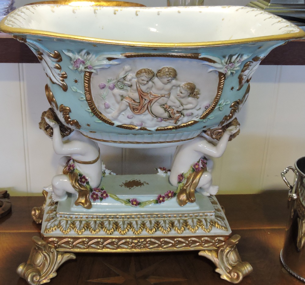 A German style porcelain centre piece, the turquoise bowl supported by two seated putti,