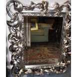 A large peer glass with Rococo style silver coloured ornate frame,