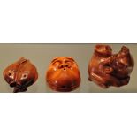 Three hardwood netsuke in the forms of two kittens,