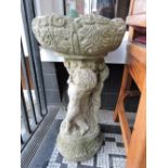 A cement bird bath, on plinth modelled as 3 putti.