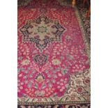 A North West Persian Tabriz style burgandy ground carpet woven with floral medallions within a