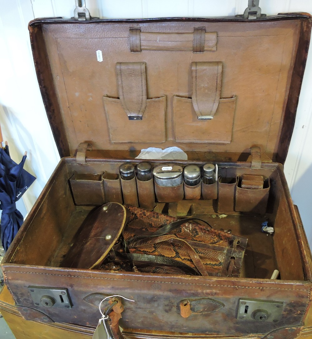 An early 20th Century tan leather gentleman's travelling toilet case, fitted five silver top jars,