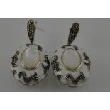 A pair of silver and white enamel earrings with a marcasite and mother of pearl centre