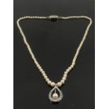 A white gold and diamond pendant suspended a round white cultured pearl, on a pearl necklace