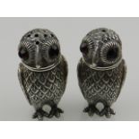 A pair of Continental white metal condiments, designed as owls with red glass eyes,