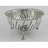 A George V silver bowl, having double beaded rim and repousse decoration, raised on three paw