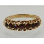 A 9 carat yellow gold and garnet half eternity ring, set seven round cut garnets.