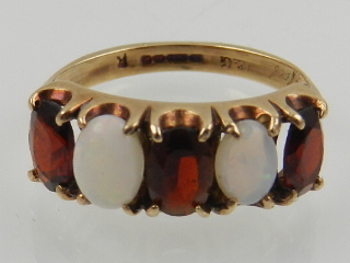 A 9 carat yellow gold, opal, and garnet five stone ring.