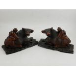 A pair of 20th century Chinese carved hardwood figural studies of a man on an ox, both on original