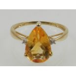 A 9 carat yellow gold and citrine ring, the pear cut citrine flanked by two diamond accents.