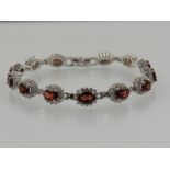 A silver, cubic zirconia, and garnet cluster bracelet.