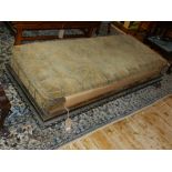 An early 20th century oak day-bed, of rectangular form with a loose cushion and lion paw feet. W.