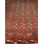 An Afghan red ground Bokhara carpet, having five rows of elephant pad medallions to centre, multi-