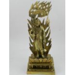 A Tibetan polished brass figural study of a deity carrying a scorpion hilted sword and having with