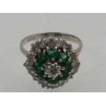 An 18 carat white gold, diamond, and emerald cluster ring,