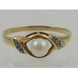 A 9 carat yellow gold and pearl crossover style ring, the shoulders set with diamond accents.