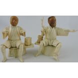 A pair of Early 20th Century carved bone figures of seated gentlemen one with a basket and staff,