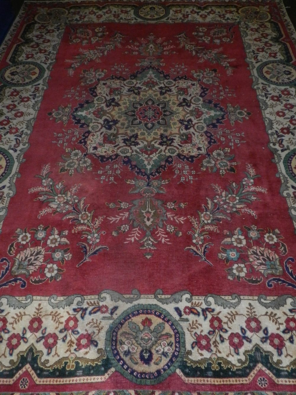 A red ground Tabriz carpet, having star shaped floral medallion to centre, multi-bordered and