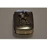 A rectangular silver box with a frog playing a guitar on the lid