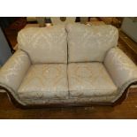 A 20th century mahogany framed camel back two seater sofa, upholstered in a cream floral fabric,