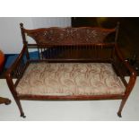 A late 19th / early 20th century mahogany two seater canape, having a carved stylised backrest,