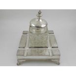A silver plate mounted cut glass ink well, raised on a silver plated base with four shaped feet.