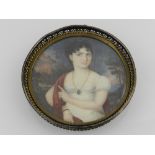 An early 19th century circular portrait miniature of a seated lady, oil on card, in a sterling