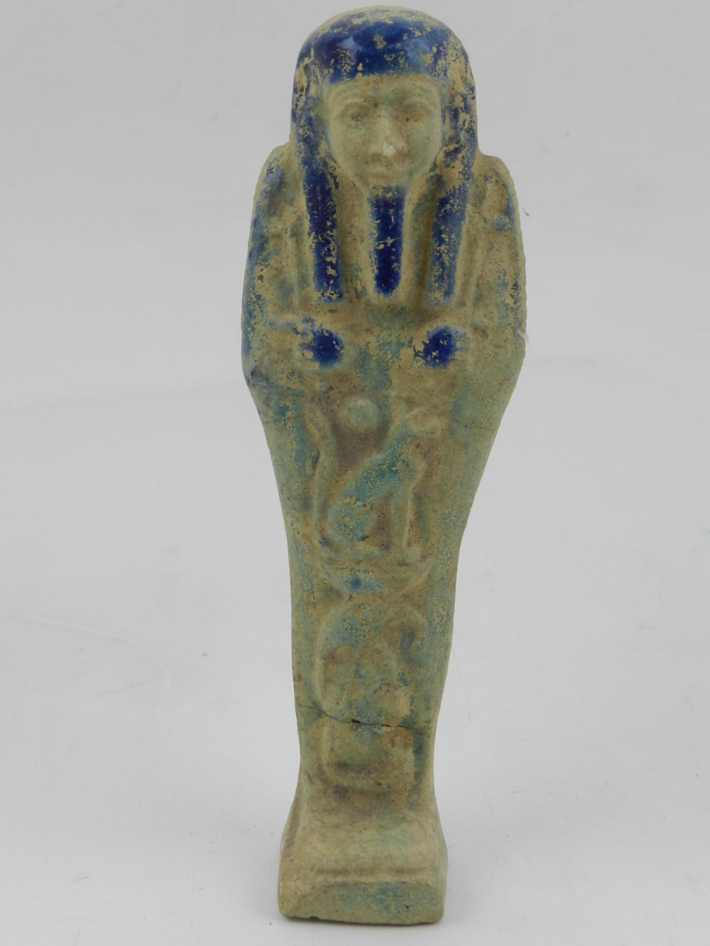 An Egyptian earthenware shabti, partially glazed in indigo, blue and turquoise. H.16cm