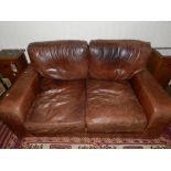 A Contemporary two-seater brown leather sofa, raised on square bracket feet.